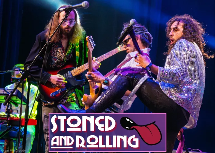 Four bandmates on stage playing instruments in costume, band name and logo