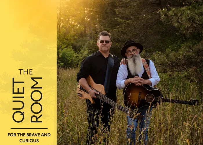 Two band members holding guitars posing together in field