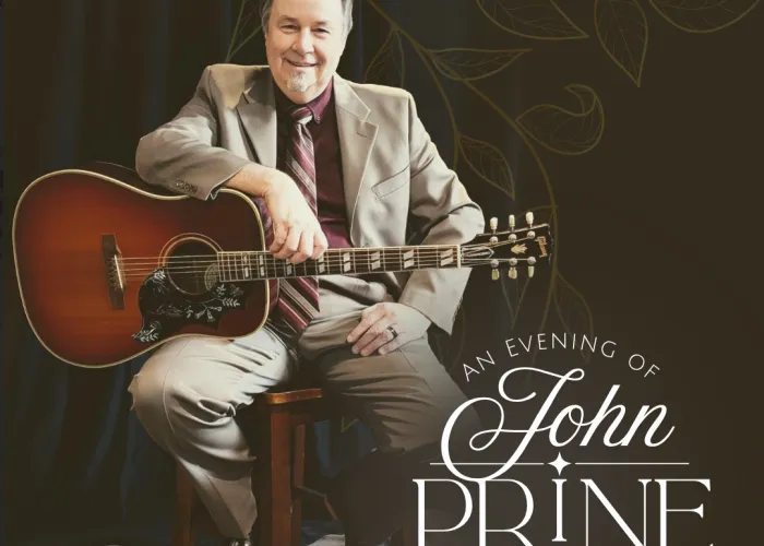 Photo of Kevin Hornsby sitting on a chair with a guitar in his lap. 