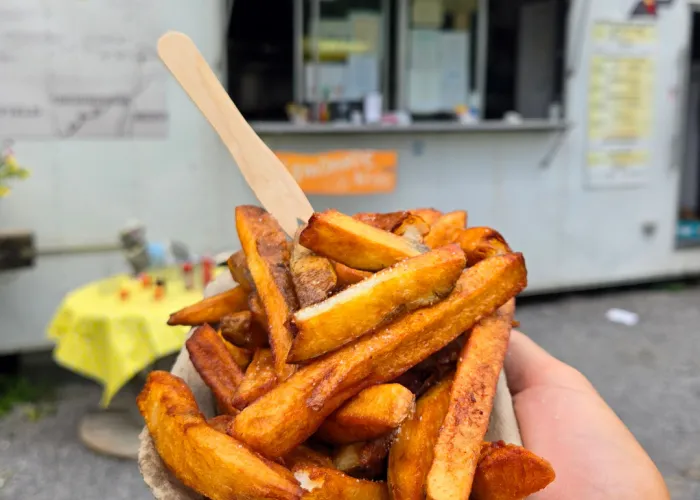 a person holding a food truck meal in front of the food truck