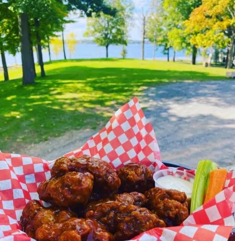 A plate full of chicken wings with a lake in the background
