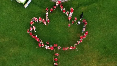 people lined up to make the shape of Canadian flag